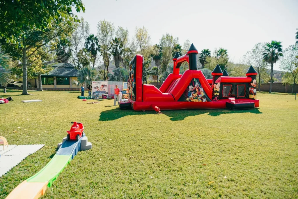 A red inflatable castle bounce house on a grassy lawn