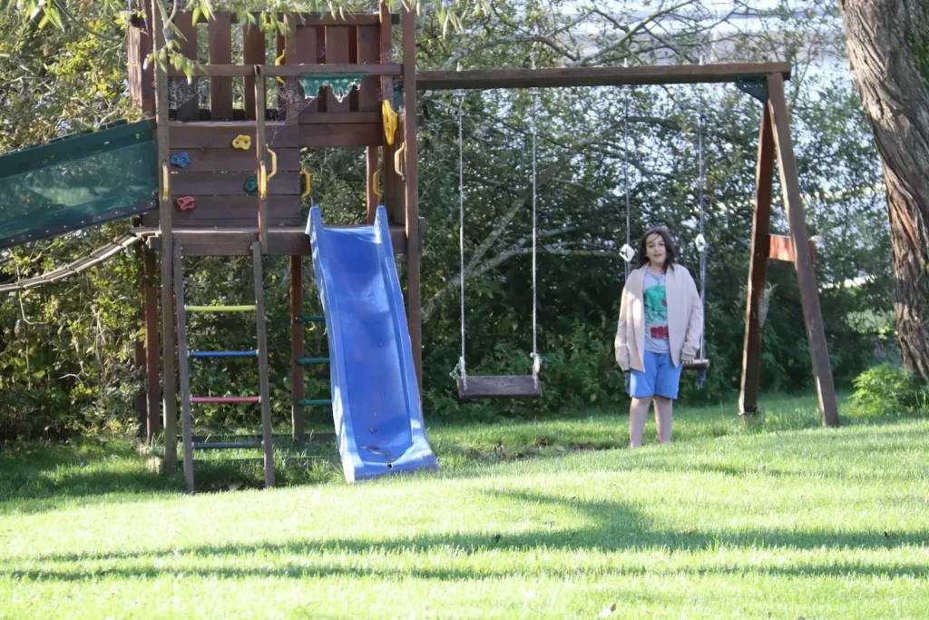 A couple of kids standing next to a blue slide