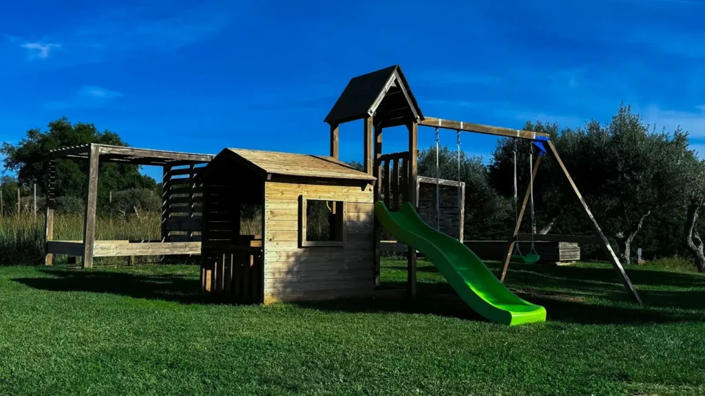 A wooden play set with a green slide