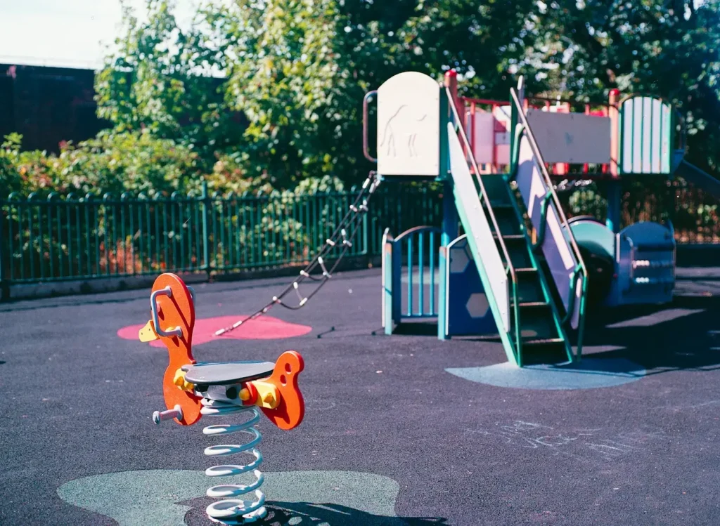 A spring rider and a playground structure on a rubber surface in a park