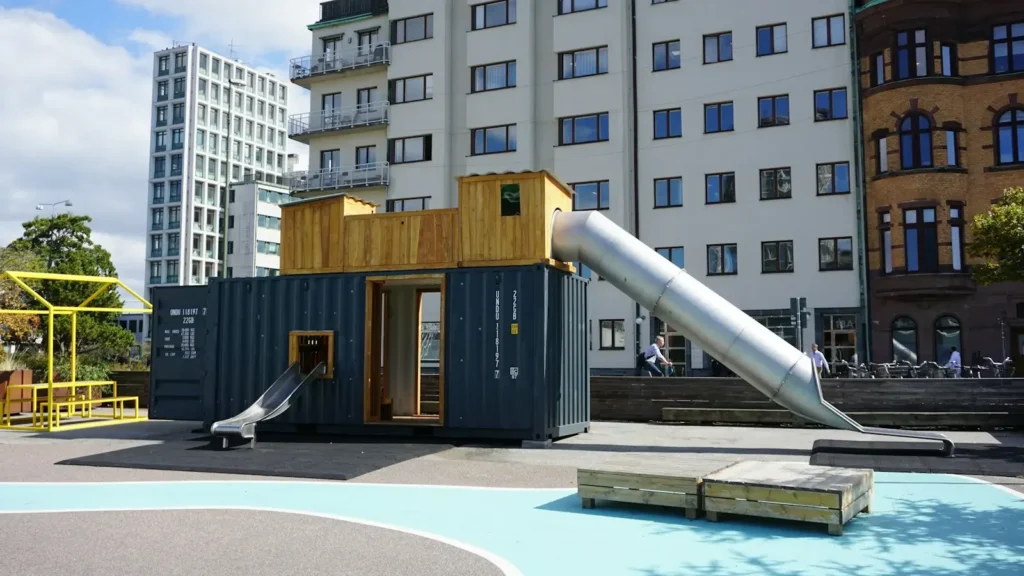 A playground structure made from a shipping container with two metal slides