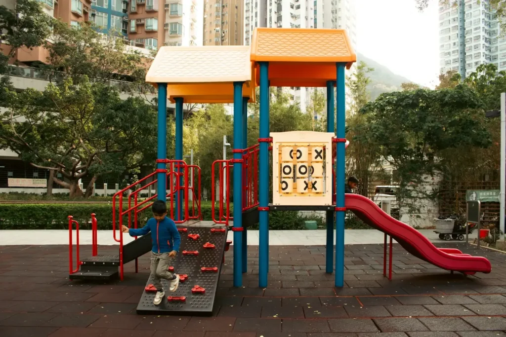 A child climbing a playground structure with a tic-tac-toe game in a park